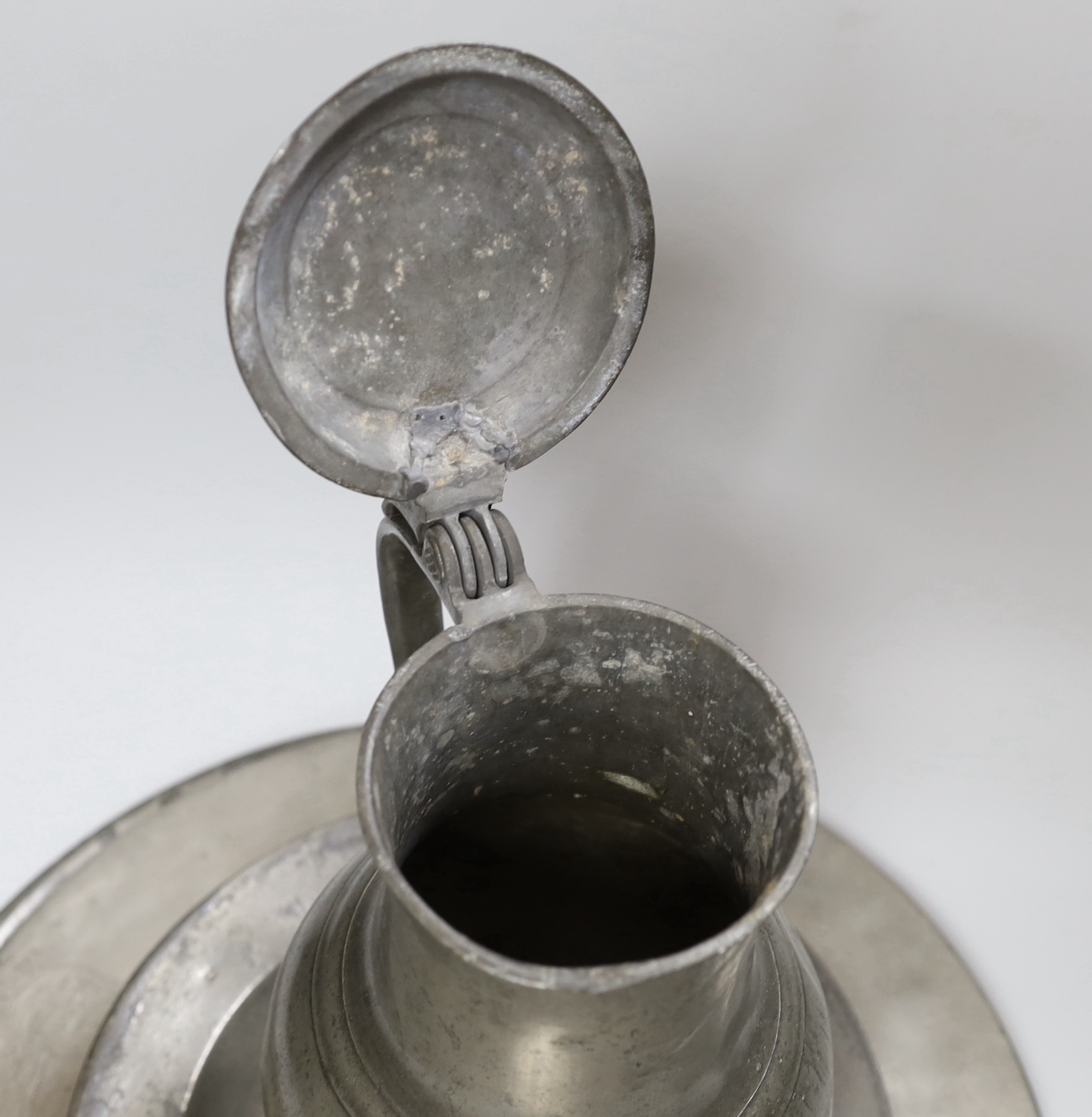 Two pewter chargers one crested, eight plates and a jug, 18th century and later, largest charger 38cms diameter